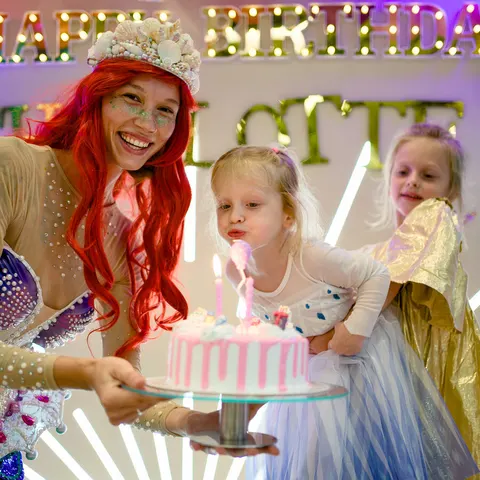 Mermaid host presenting a birthday cake to the birthday girl