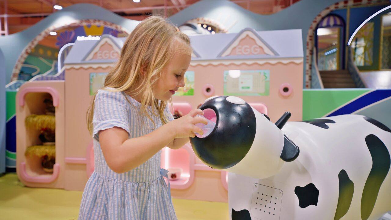 Girl exploring the farm sensory zone with a play cow