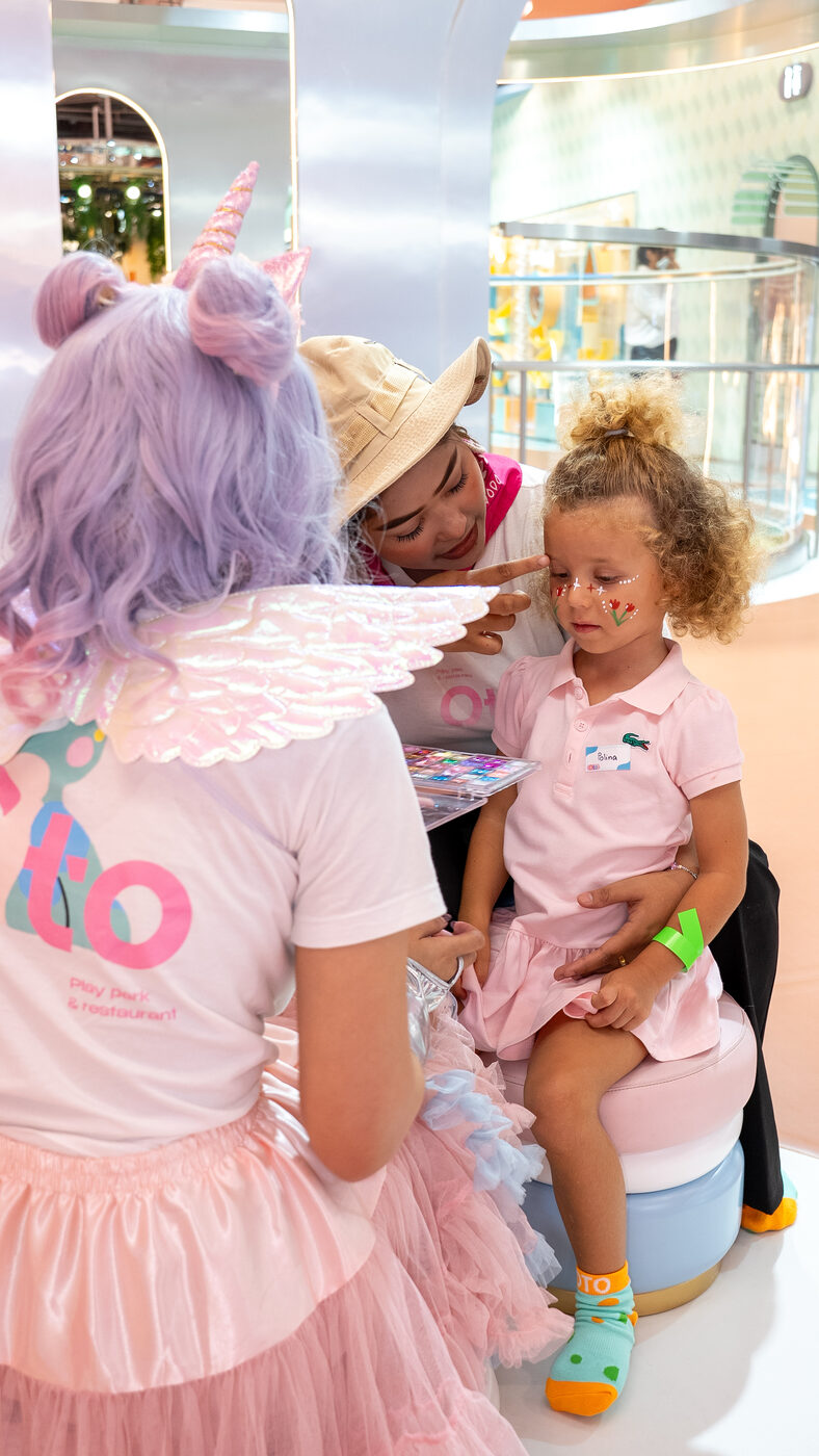 OTO nannies giving a child a unicorn face paint