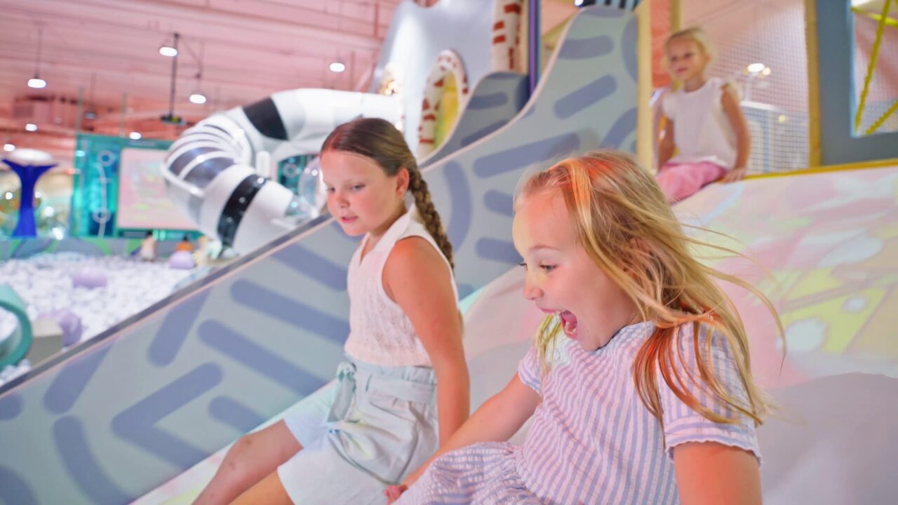 Children racing down the giant indoor slide
